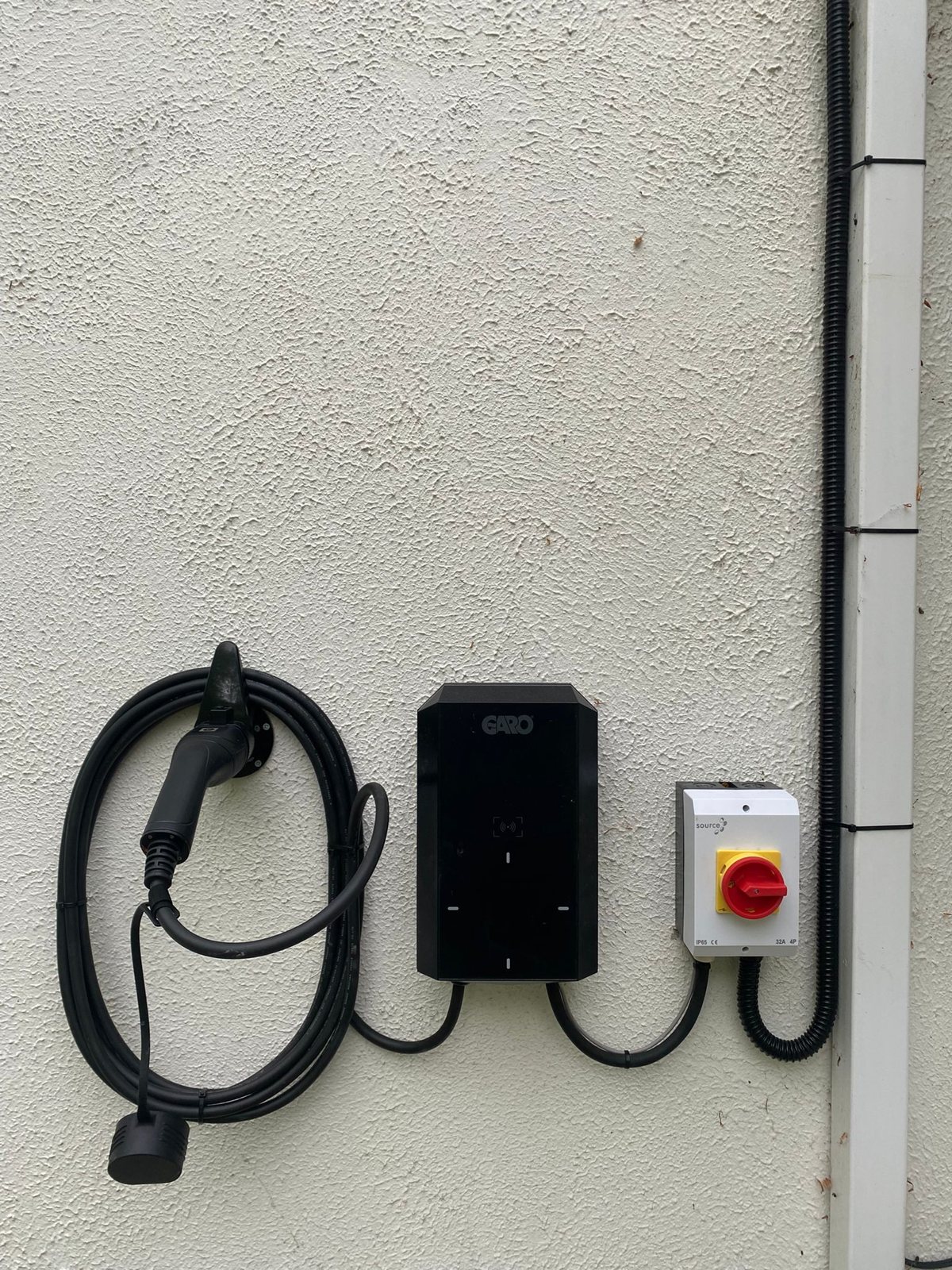 A wall-mounted EV charger with its isolator switch