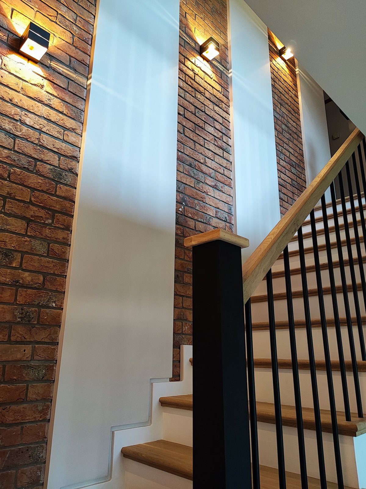 Wall lights on a brick wall above a staircase